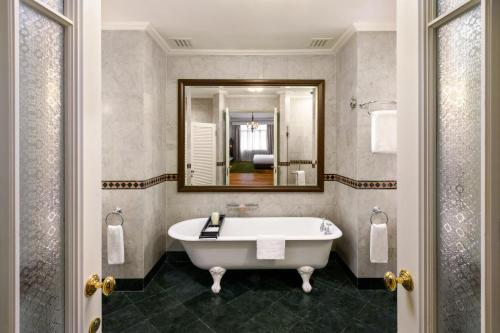 a bathroom with a tub and a mirror at Eastern & Oriental Hotel in George Town