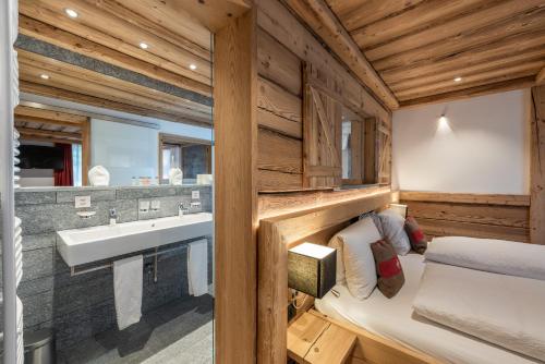 baño en una cabaña de madera con lavabo y cama en Hotel Crusch Alba Zernez, en Zernez