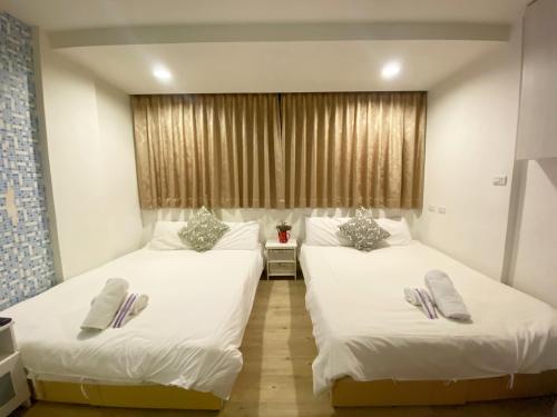 two beds in a room with white sheets and pillows at Day Day Fengjia in Taichung