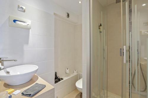 ein Bad mit einem Waschbecken und einer Glasdusche in der Unterkunft Urban Style hotel de l'Europe in Rouen