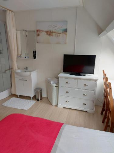 a bedroom with a white dresser with a flat screen tv at Bed & Breakfast d'Ouwe Smidse in Kamperland