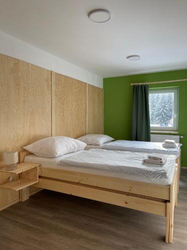 a bed in a room with a green wall at Penzion Mája in Josefuv dul