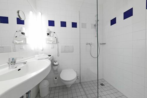 uma casa de banho com um WC, um lavatório e um chuveiro em Hotel Plaza Hannover em Hanôver