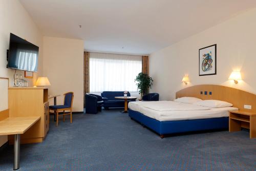 ein Hotelzimmer mit einem Bett, einem Tisch und Stühlen in der Unterkunft Hotel Plaza Hannover in Hannover