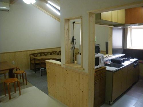 a kitchen with a counter with a microwave and a table at すまいるハウス in Teine