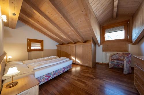 Residence Lagorai - Fiemme Holidays في بريدازو: غرفة نوم بسرير كبير وسقف خشبي