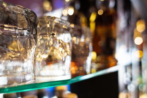 a row of glasses on a shelf with bottles at Urban Style hotel de l'Europe in Rouen