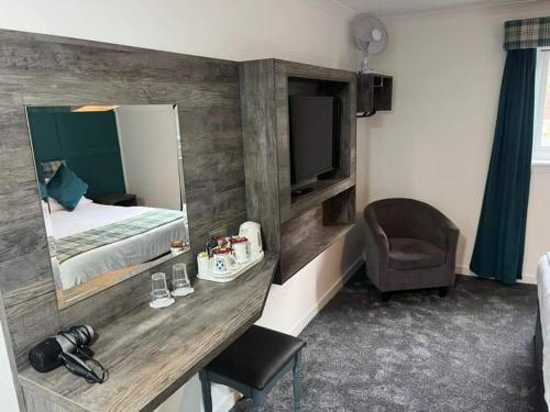 a room with a bed and a desk with a television at MacDonald Hotel & Cabins in Kinlochleven