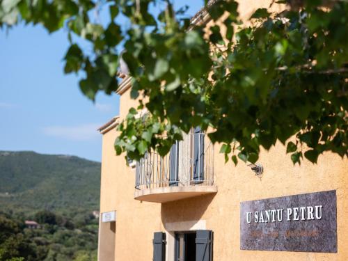 - un bâtiment avec un balcon et un panneau sur celui-ci dans l'établissement Hôtel - Restaurant U Santu Petru, à Saint-Florent