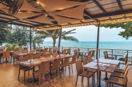 a restaurant with tables and chairs and the ocean at Sand Dunes Chaolao Beach Resort in Chao Lao Beach