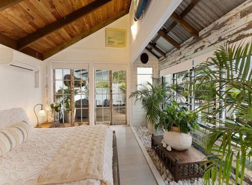 a bedroom with a bed and potted plants in it at Sunset on Noosa Chalet in Noosa Heads