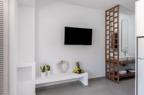 a white living room with a white bench and a television at Kellys Luxury Apartments in Faliraki