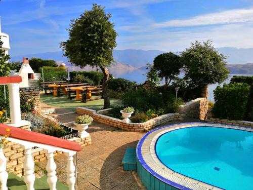 a swimming pool in a garden with a view of the water at Family Apartments K&M in Pag