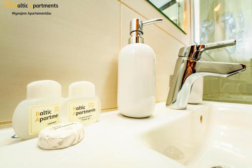 a bathroom sink with a bottle of soap and a soap dispenser at Baltic Apartments - Apartamenty Aquamarina in Świnoujście