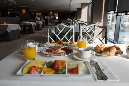 a table topped with plates of food and fruit at Hotel Bahía in Santander