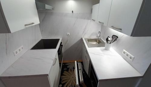 a small kitchen with white cabinets and a sink at ADRIAN Seeblick Appartement, Haus Hänsel&Gretel direkt am Ossiacher See mit Hallenbad, Skiarena Gerlitzen in Steindorf am Ossiacher See
