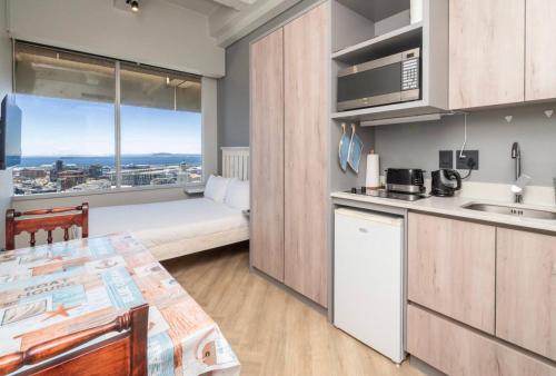 a kitchen with a table and a bed in a room at Cosy Studio with Spectacular Views in Cape Town