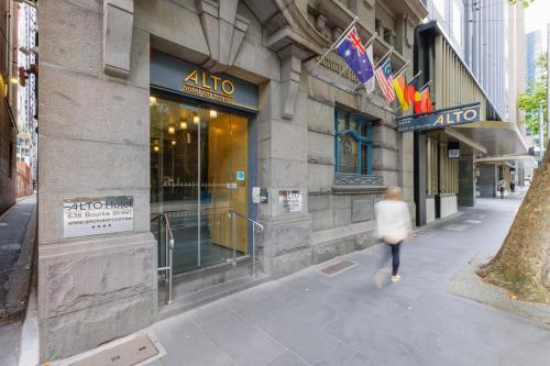 een vrouw die over een stoep loopt voor een winkel bij Alto Hotel On Bourke in Melbourne