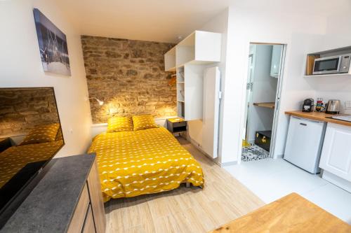 - une chambre avec un lit jaune et un mur en pierre dans l'établissement LES NIDS DE SAINT MARC - centre-ville, à Quimper