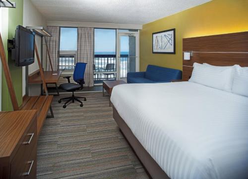 Habitación de hotel con cama, escritorio y TV. en Holiday Inn Express Nags Head Oceanfront, an IHG Hotel en Nags Head