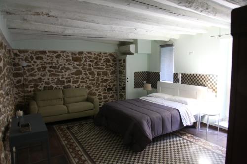 1 dormitorio con cama y pared de piedra en Chiarastella Rooms en Villafrati