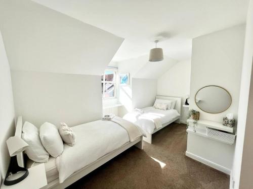 a white bedroom with two beds and a mirror at Lovely 2-Bed House in St Andrews Scotland in St. Andrews