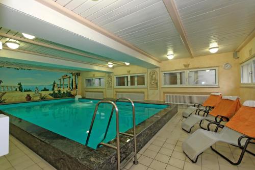 een zwembad in een kamer met stoelen en een zwembad bij Hotel Waldfrieden "Das kleine Hotel" in Spiegelau