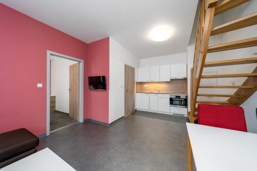 a living room with a red wall and a kitchen at Pension Janský Potok II. in Janske Lazne