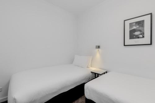 a bedroom with two beds and a picture on the wall at Alto Hotel On Bourke in Melbourne
