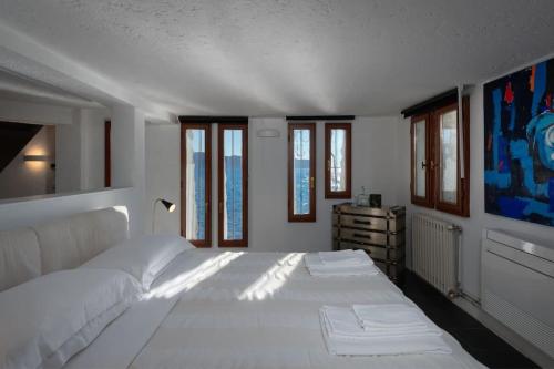 a large white bed in a room with windows at Villa Anna in Toscolano Maderno
