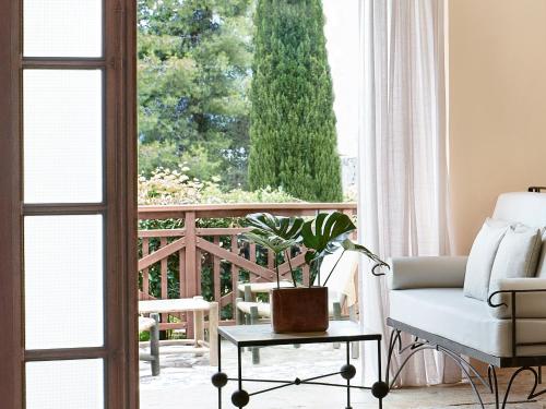 a living room with a chair and a window at Grecotel LUXME Daphnila Bay in Dassia