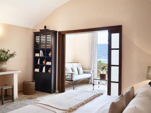 a bedroom with a bed and a living room with a window at Grecotel LUXME Daphnila Bay in Dassia