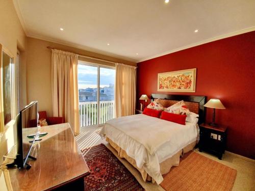 1 dormitorio rojo con 1 cama y ventana grande en Luxury Villa in Pinnacle Point with Inverter en Mossel Bay