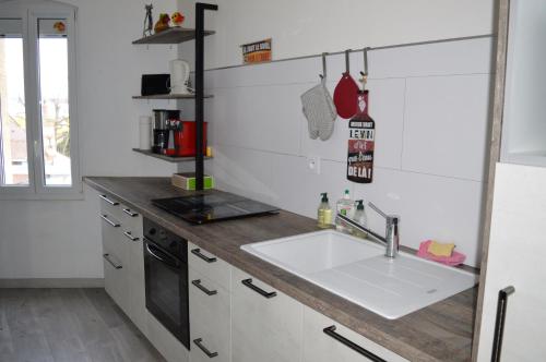 a kitchen with a sink and a stove at Appartement près du port centre et plage - Vue mer in Courseulles-sur-Mer