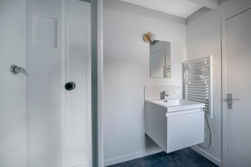 een witte badkamer met een wastafel en een douche bij Charmant appartement en plein centre du Pouliguen! in Le Pouliguen
