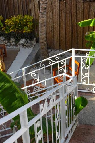 a white fence with orange chairs in a garden at Dar Mar Hostel & Coworking in Paje
