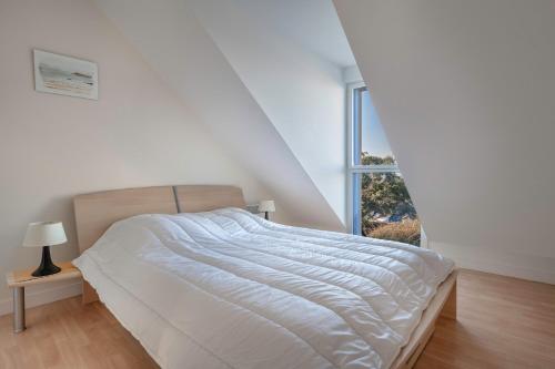a white bedroom with a bed and a window at Maison lumineuse, pour 8, avec vue sur mer in Saint-Gildas-de-Rhuys