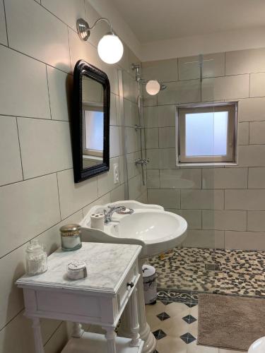 une salle de bain blanche avec un lavabo et un miroir dans l'établissement La Glycine, à Tonnac