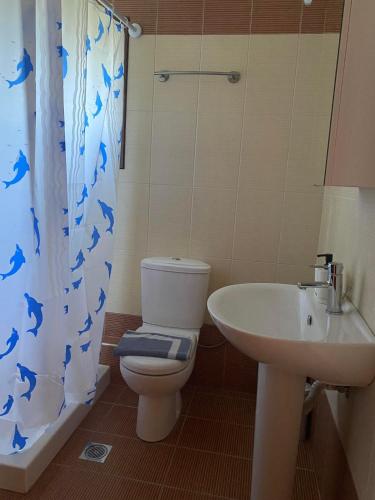 a bathroom with a toilet and a sink and a shower curtain at Luna Bay in Agios Ioannis Pelio