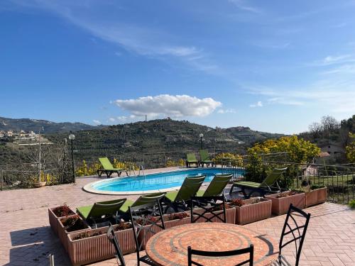 a swimming pool with chairs and a table and a tablektop at Agriturismo Le Mimose in Imperia