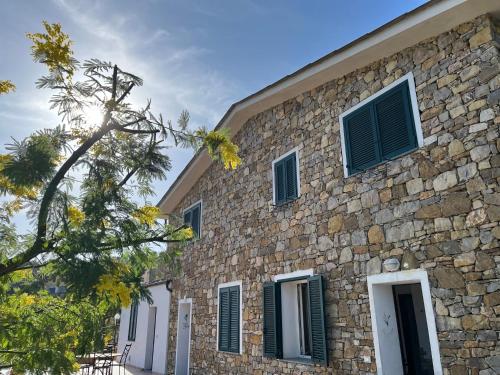 a stone building with green shutters on it at Agriturismo Le Mimose in Imperia