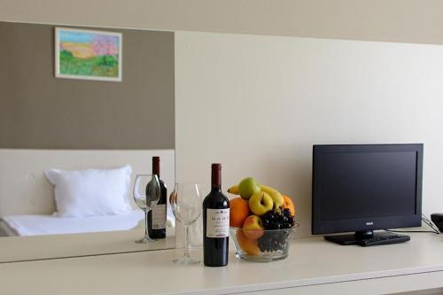 a table with two bottles of wine and a bowl of fruit at Парк хотел Кюстендил in Kyustendil