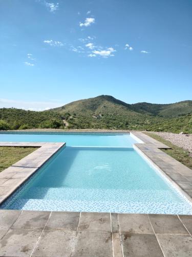 a blue swimming pool with mountains in the background at Potrero del Rey in Estancia Grande