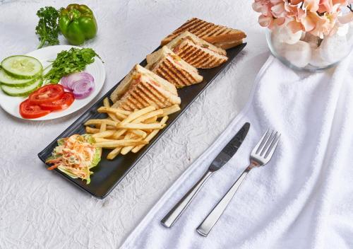 a black plate of food with a sandwich and french fries at E Hotel in Chennai