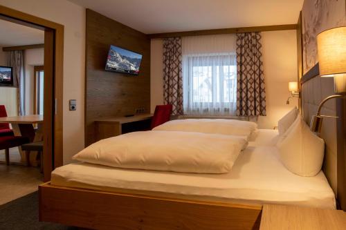 a bedroom with a large white bed with a window at Gidis Hof in Ischgl
