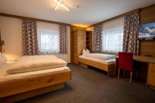 a bedroom with two beds and a desk and a tv at Gidis Hof in Ischgl