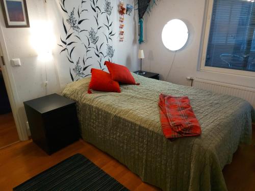 a bedroom with a bed with two red pillows on it at City Apartment Tulliportti in Kuopio