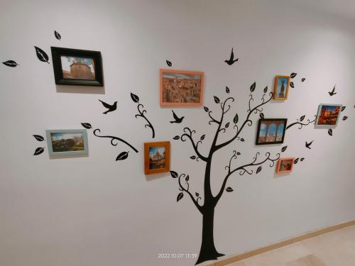 un árbol con fotos y pájaros en una pared en Tirwal Suite Judería, en Teruel