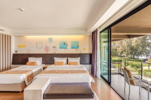 two beds in a room with a balcony at Sand Dunes Chaolao Beach Resort in Chao Lao Beach