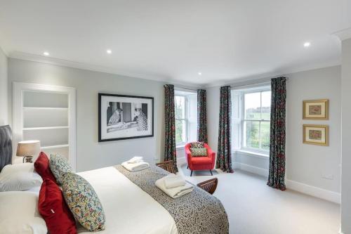 a bedroom with a large bed and a red chair at Greenmyre Farmhouse with Hot Tub in Kirriemuir